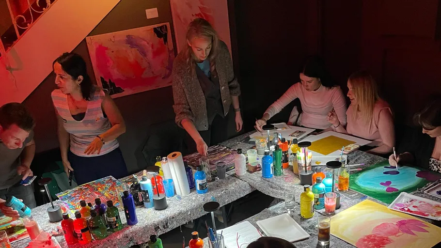 People painting at a table in dim room.