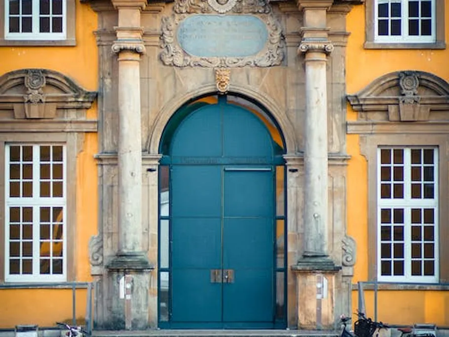 Große, bunte Tür öffnet sich zu einem historischen Gebäude.