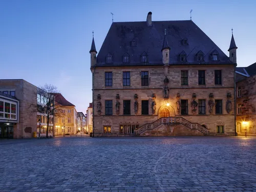 Huge building with stairs illuminated at dusk.