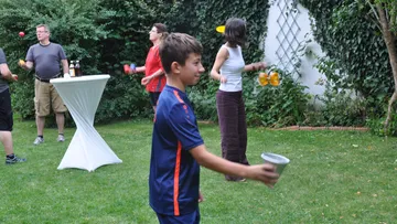 People juggle in a garden setting.