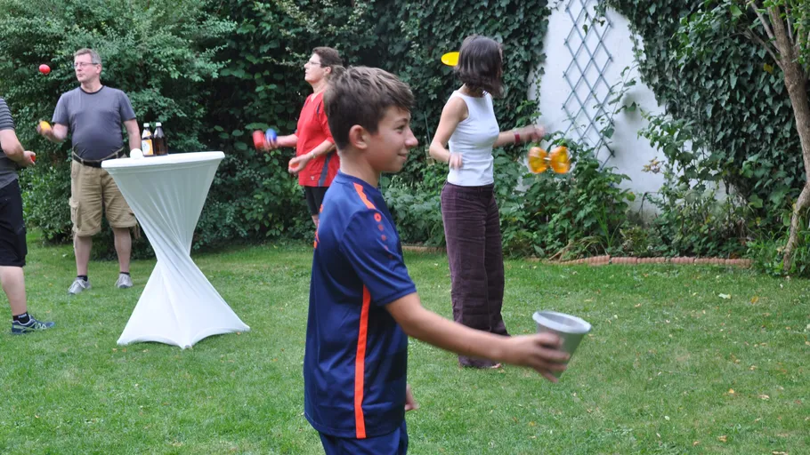 Menschen jonglieren in einem Garten.