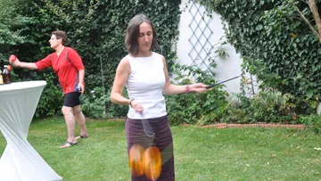 Frau jongliert Poi im Gartensetting.