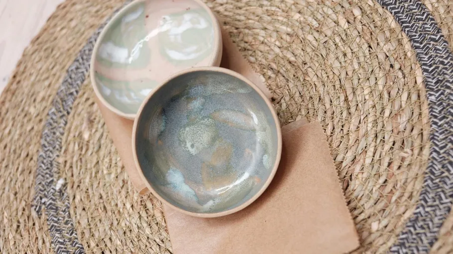 Two ceramic bowls placed on a woven mat.
