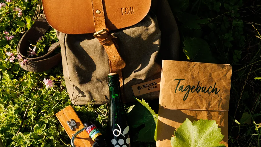 Backpack and diary in grass with bottle.