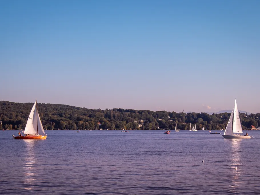 Two sailboats sail quietly on a lake.