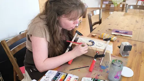 Woman painting on wood at a table workshop.