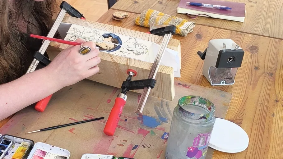 Woman painting on wood at a table workshop.