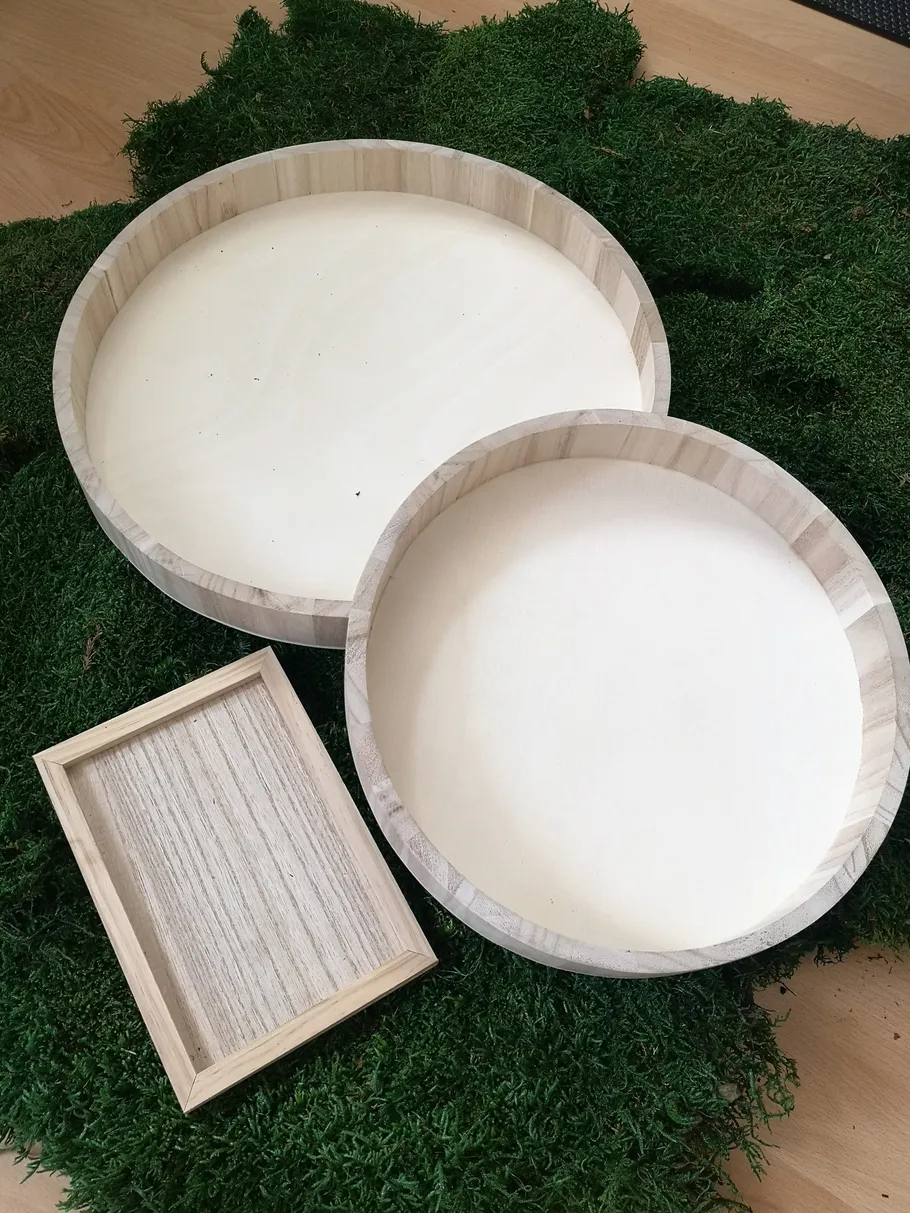 Zwei Holztabletts auf grüner Moosfläche.