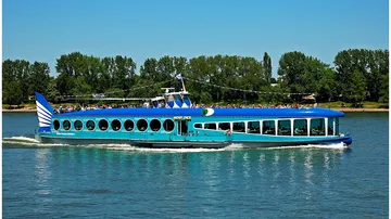 Blaues Flussboot fährt auf sonnigem Fluss.