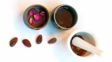 Tassen mit Kakao, Rosenblätter und Mörser.