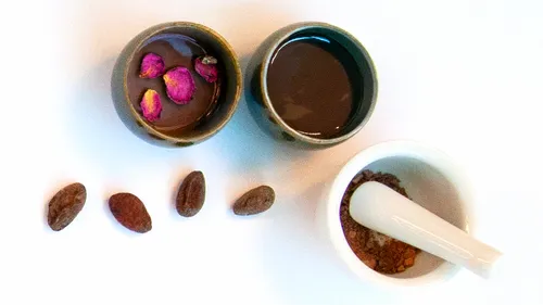 Tassen mit Kakao, Rosenblätter und Mörser.