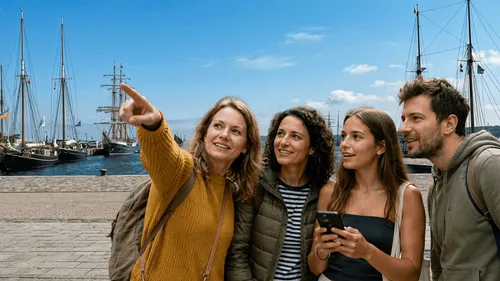 Group pointing at ships, enjoying harbor view.