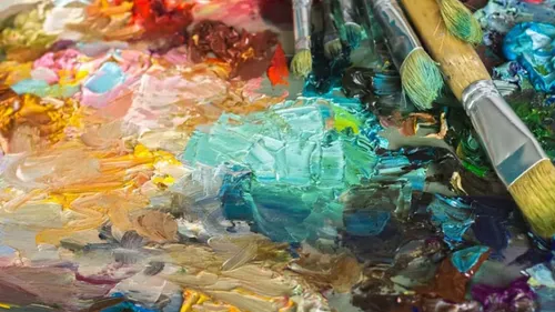 Paintbrushes rest on colorful paint palette.
