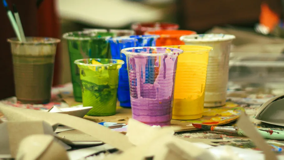 Plastic cups with colorful paints on table.