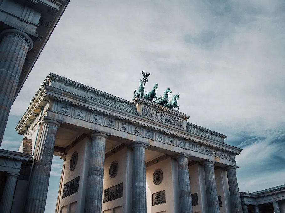 Gate with pillars, horses on top, against a cloudy sky.