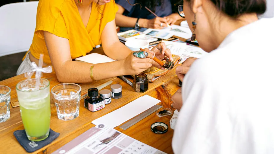 Menschen malen an einem Holztisch-Workshop.