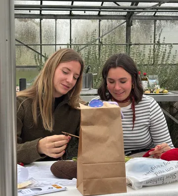 Zwei Frauen basteln in einem Gewächshaus.