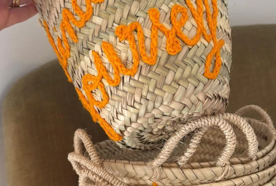 Geflochtener Korb mit orangefarbener Schrift.