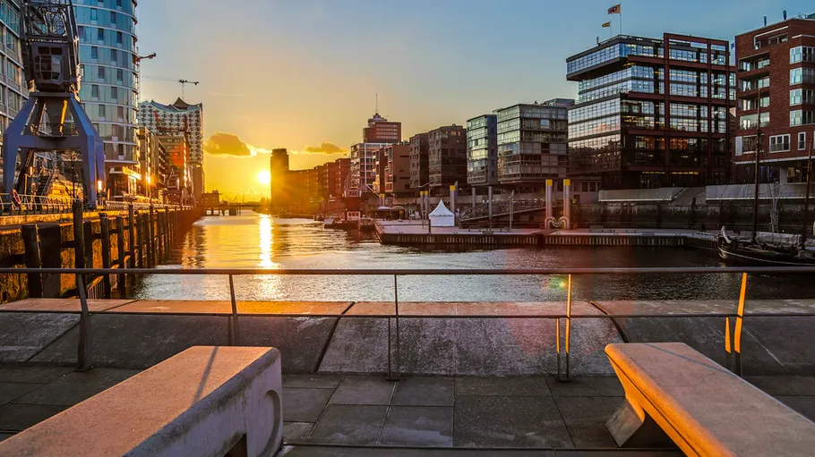 Sonnenuntergang über Wasser in Stadt mit Bänken.