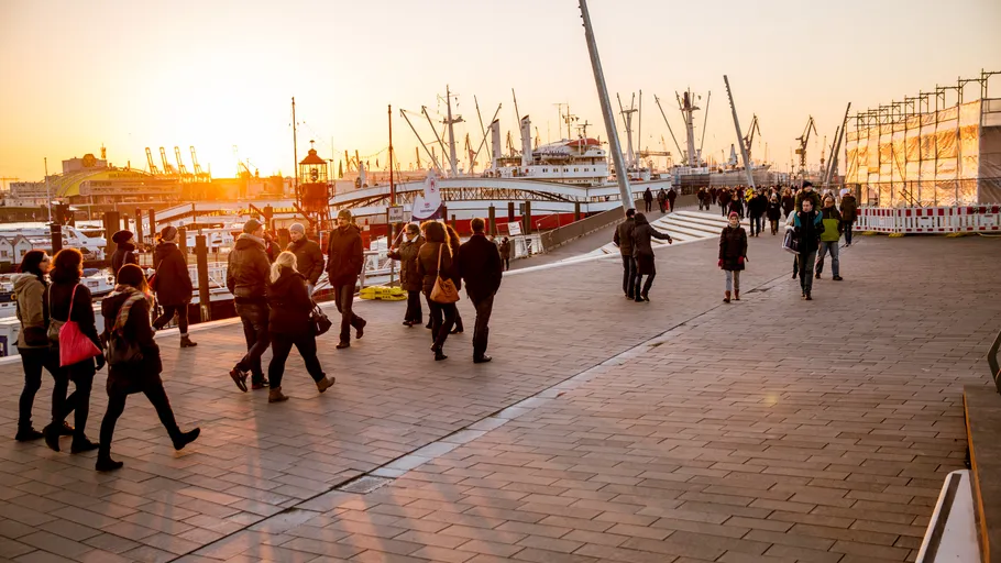 People walking near harbor at sunset.