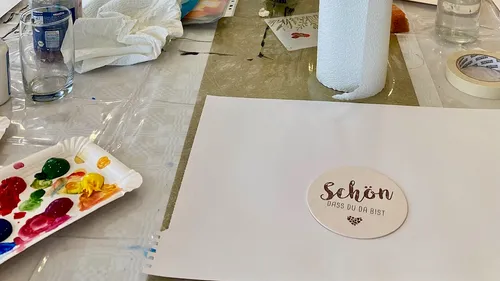 Art supplies and paper on cluttered table.