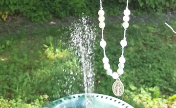Rosenkranz hängt über einem Gartenbrunnen.