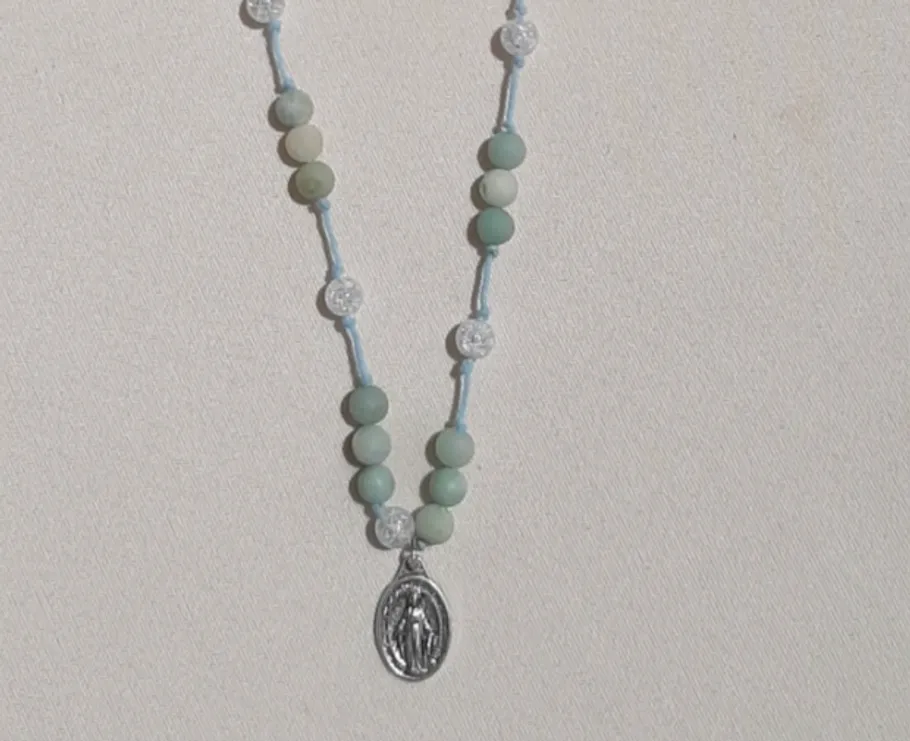 Rosary with green beads on white background.