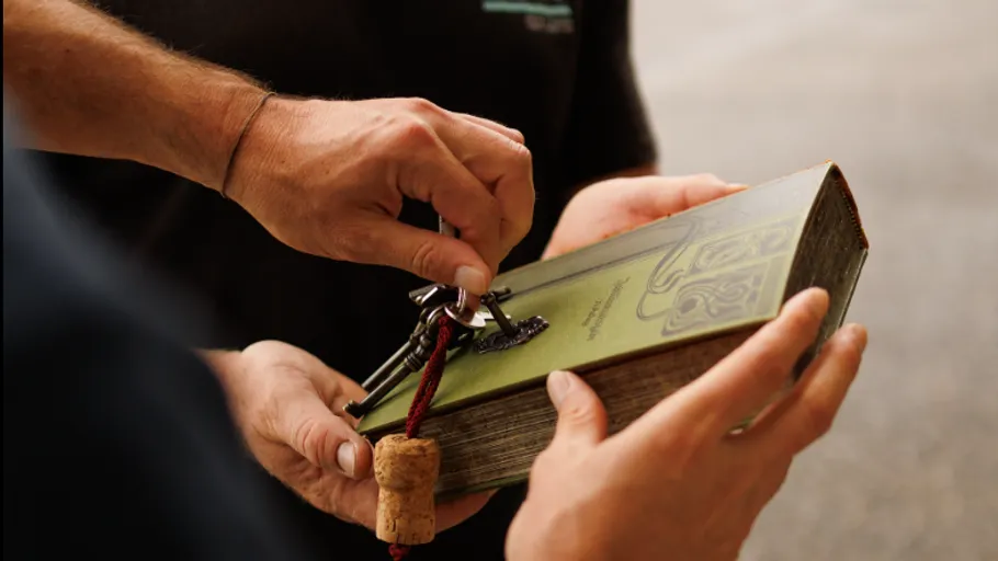 Hands exchanging a book with a key.