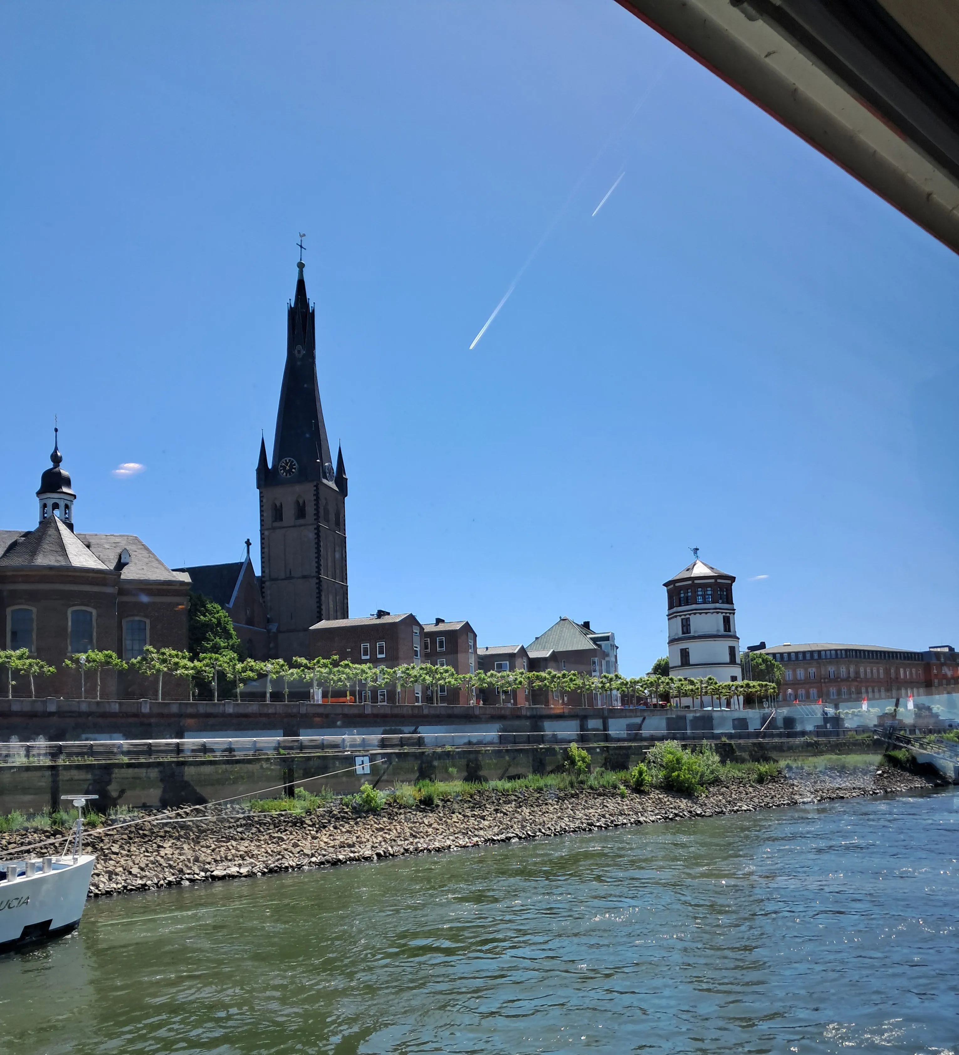 Riverside view with historic buildings under blue sky.