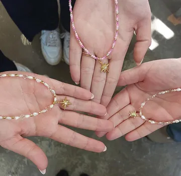 Hands holding beaded necklaces with star pendants.