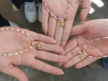 Hands holding beaded necklaces with star pendants.