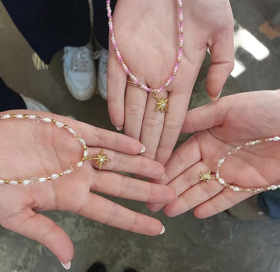 Hands holding beaded necklaces with star pendants.