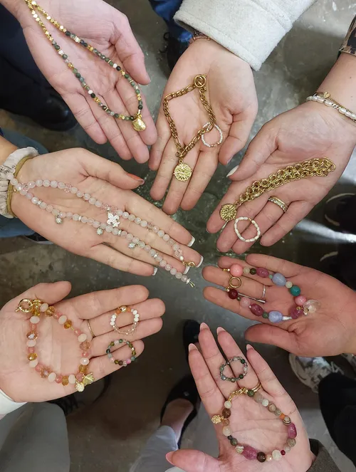 Hands displaying various handmade jewelry pieces.