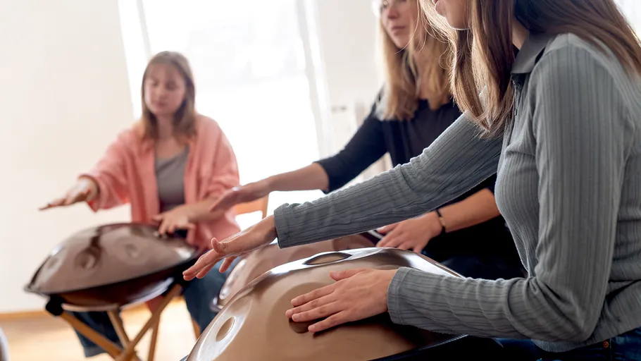 Three women playing handpans in a room.
