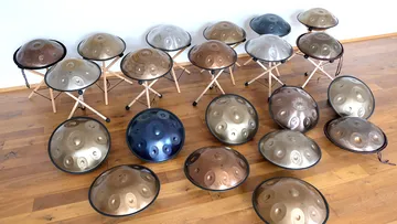 Mehrere Handpans auf Holzboden und Ständern ausgestellt.