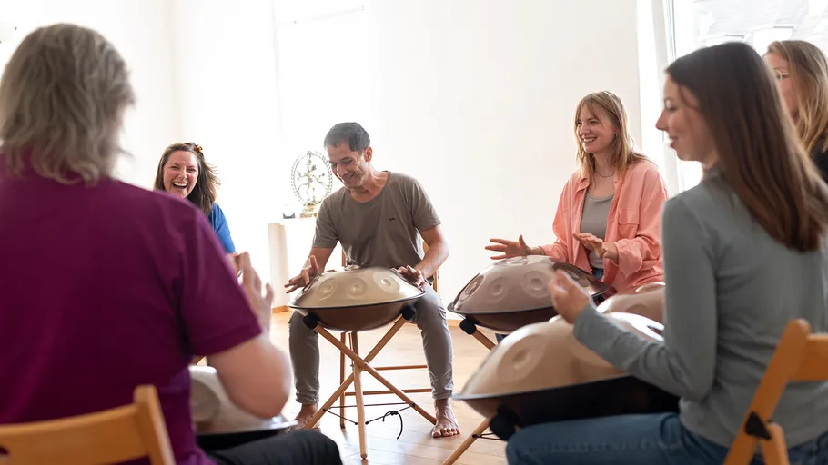 Group playing handpans in a bright room.