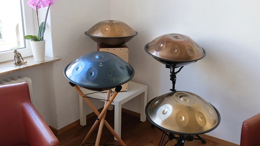 Four handpans on stands in a room corner.