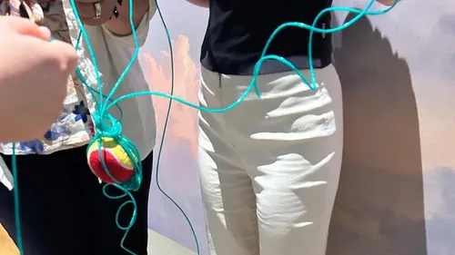 Hände halten verhedderte Schnüre mit einem Ball.