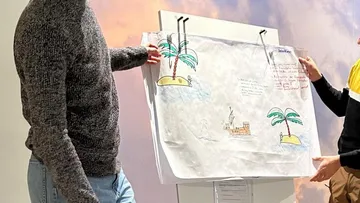 Zwei Personen präsentieren eine Zeichnung auf Papier.