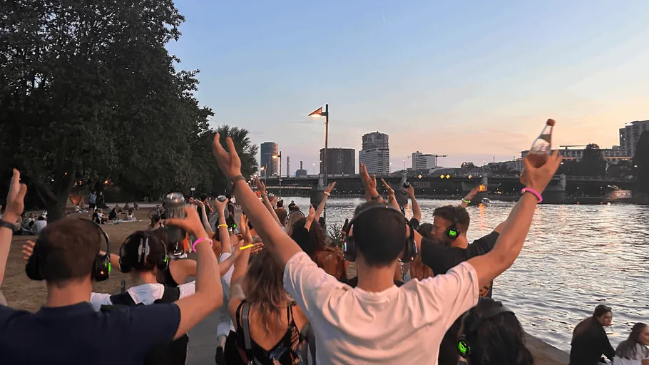 People dancing with headphones near a river.