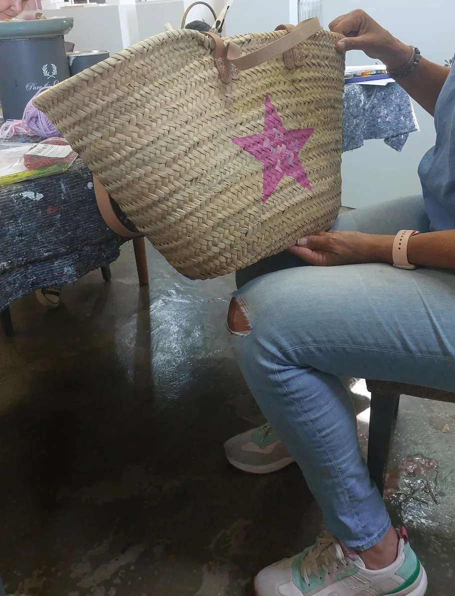 Frau hält Strohtasche mit pinkem Stern.