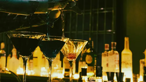 Barkeeper schenkt Cocktails in dunkel beleuchteter Bar ein.