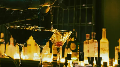Bartender pouring drinks into cocktail glasses.