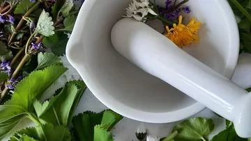 Mortar and pestle with flowers and leaves.