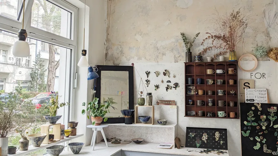 Interior with pottery, plants, and wooden shelves.
