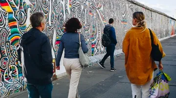Personen gehen an bunter Graffiti-Wand vorbei.