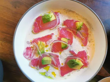 Roher Fisch mit Avocado und Sauce in flacher Schale.