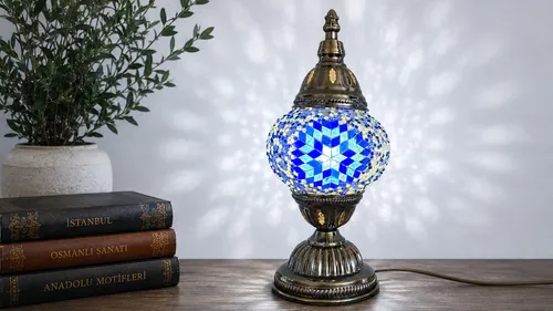 Mosaic lamp illuminating near old books on table.