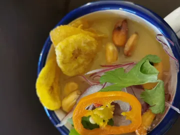 Schüssel mit Suppe, belegt mit Gemüse und Kräutern.