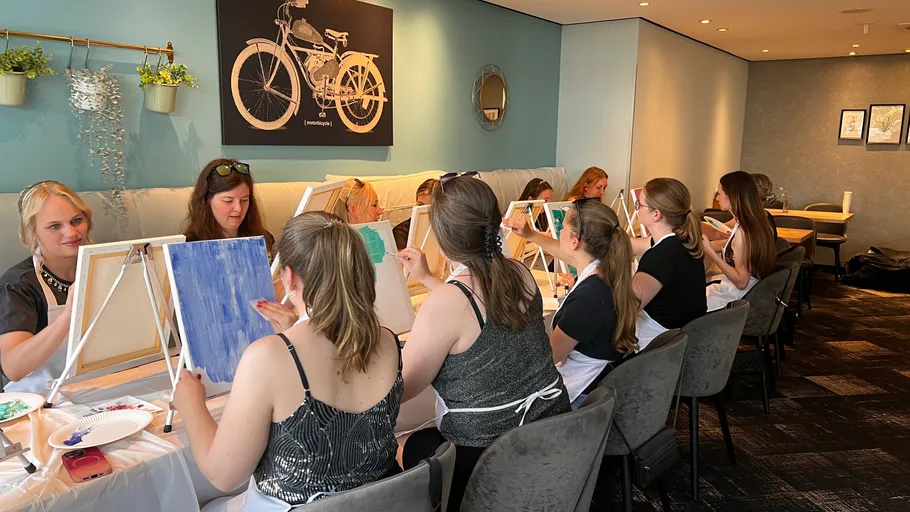 Frauen malen Leinwände in einem Workshop-Raum.